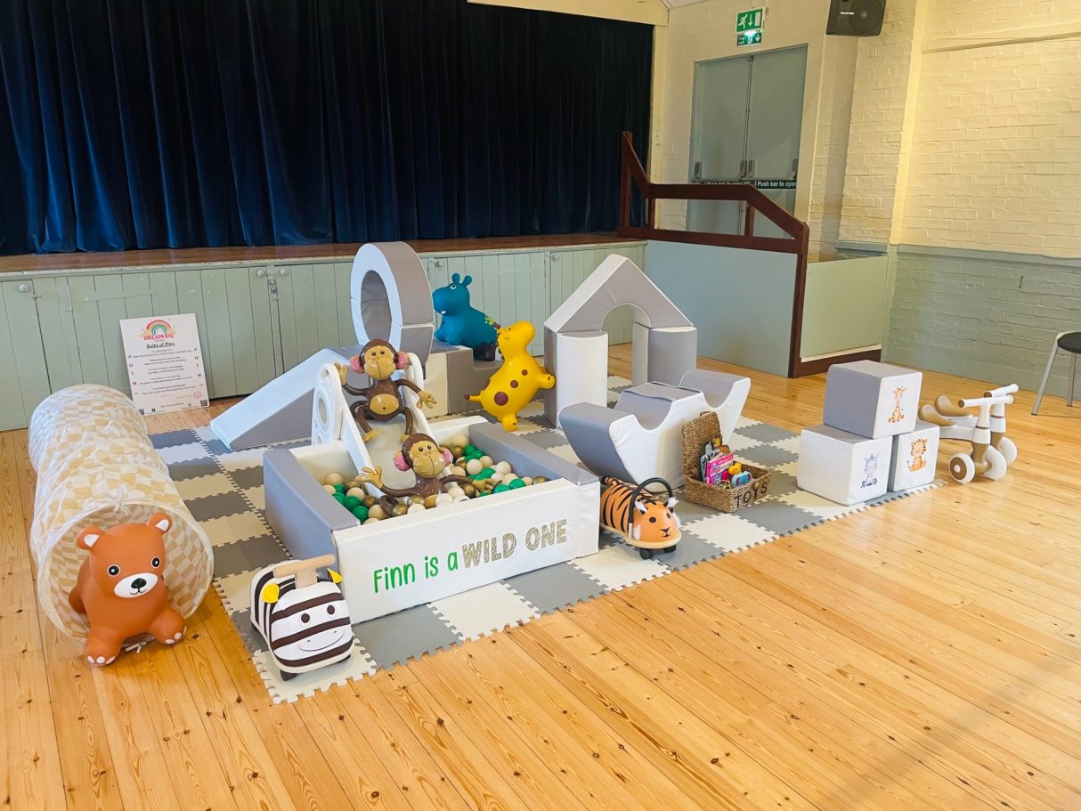 A colourful play area with soft toys and interactive structures for children.
